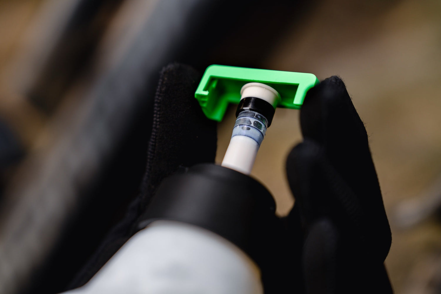 Magic Milk green cap removing a tubeless valve core — built-in tool for sealant top-ups